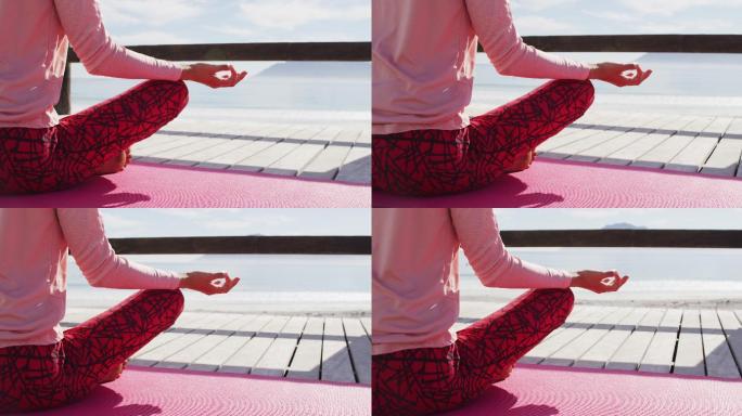 一个混血女子在户外练习瑜伽，坐在海边冥想