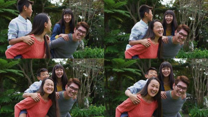 微笑的亚洲父亲和母亲猪背快乐的儿子和女儿在花园