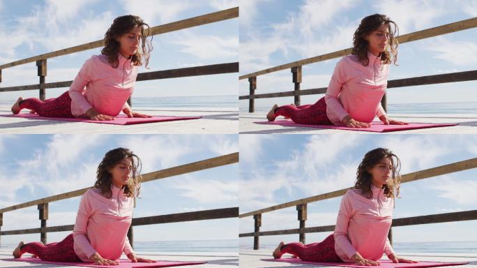 健康的混血女子在户外练习瑜伽，躺在海边，眼睛闭着