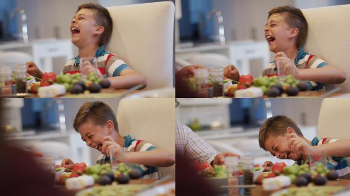 快乐的白种人孙子在餐桌上笑，坐在爷爷旁边的家庭用餐