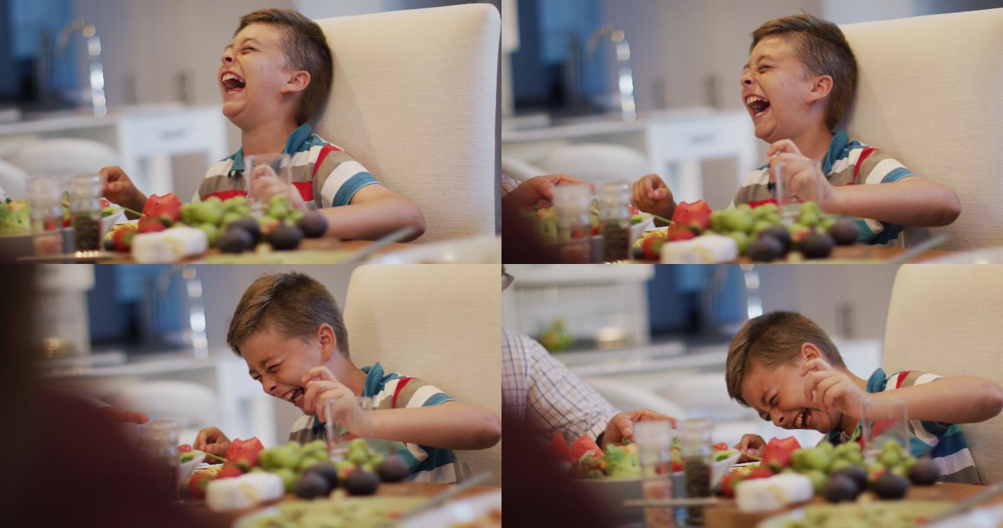 快乐的白种人孙子在餐桌上笑，坐在爷爷旁边的家庭用餐