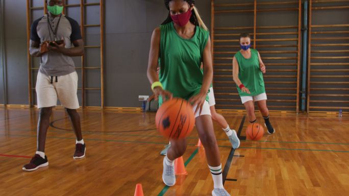 不同的女子篮球队和教练戴着面具练习运球