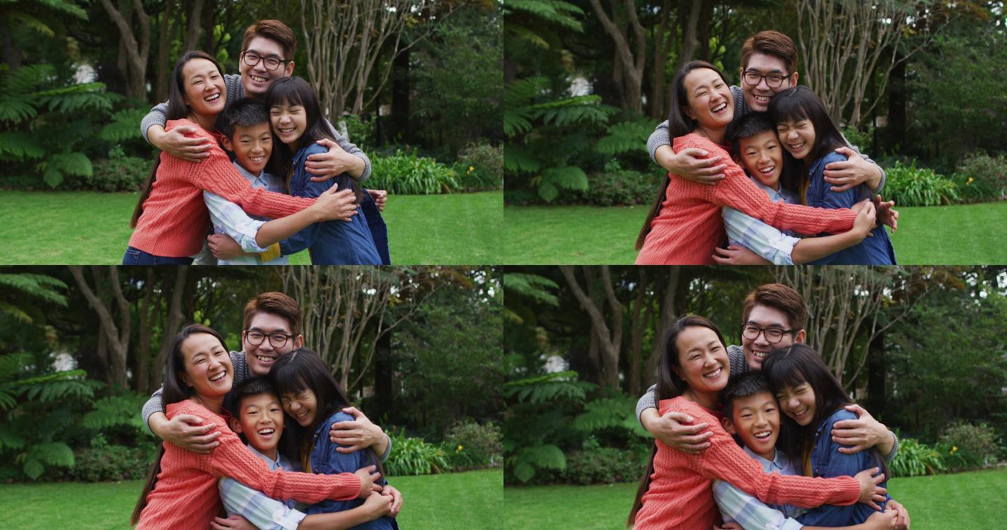 笑容满面的亚洲父母在花园里拥抱快乐的儿子和女儿