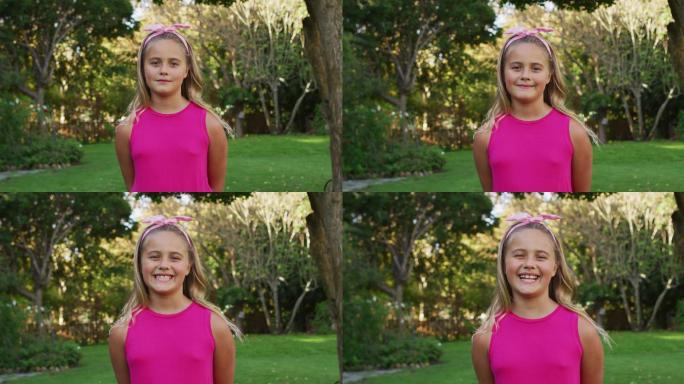 快乐的白人女孩站在花园对着相机微笑的肖像