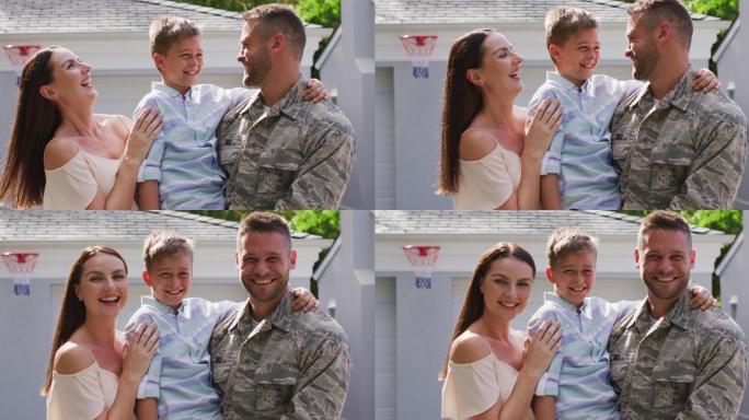 快乐的白人男性士兵拥抱他微笑的儿子和妻子在花园外的房子