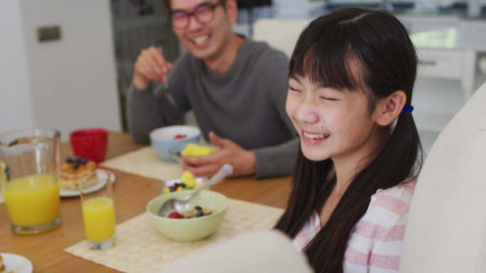 快乐的亚洲父亲在厨房吃早餐，笑儿子和女儿