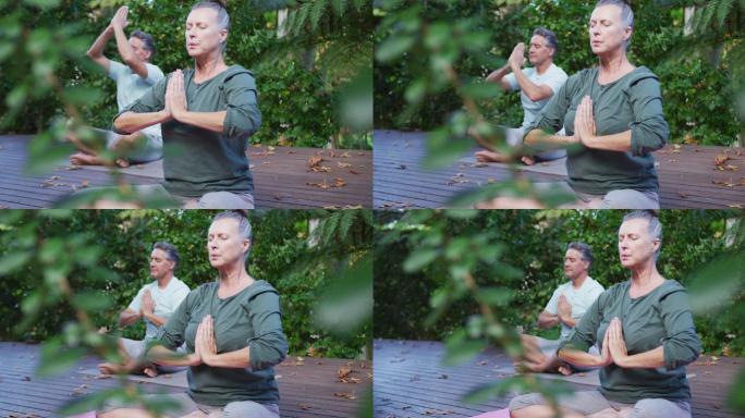 轻松的资深白人夫妇快乐地练习瑜伽，坐在花园里冥想