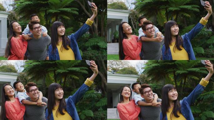 快乐的亚洲女儿与快乐的母亲自拍，父亲背着弟弟，在花园