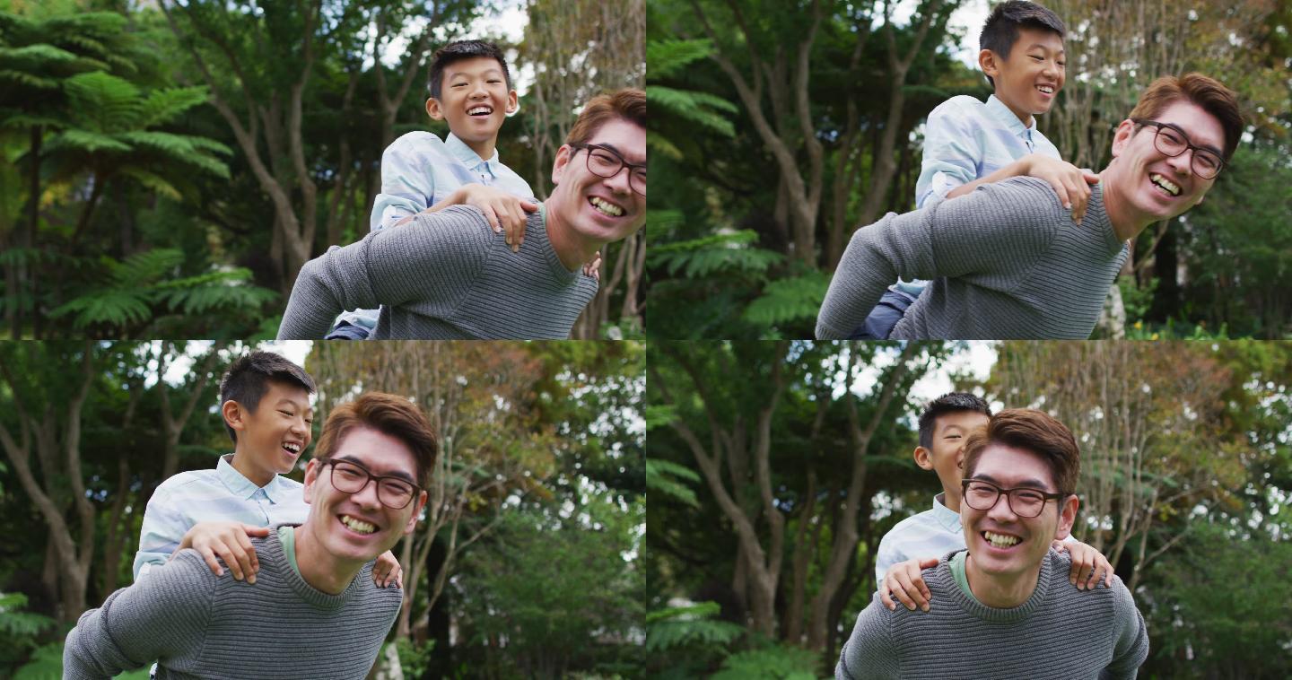 微笑的亚洲父亲猪背快乐的儿子在花园里玩在一起