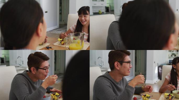 快乐的亚洲父母在厨房吃早餐和谈笑风生的女儿
