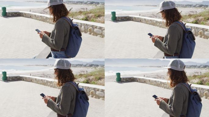 一名混血女子在海边阳光明媚的散步路上使用智能手机