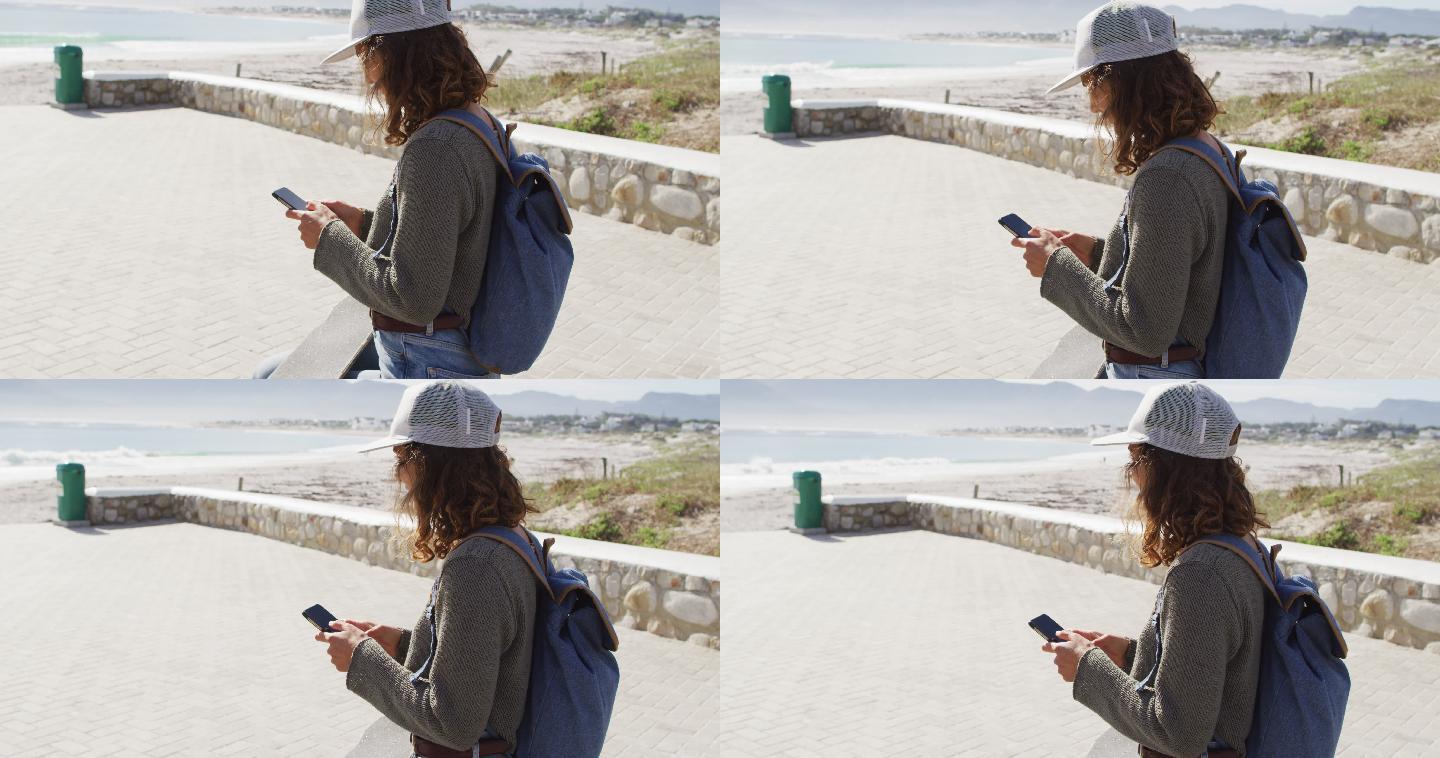 一名混血女子在海边阳光明媚的散步路上使用智能手机