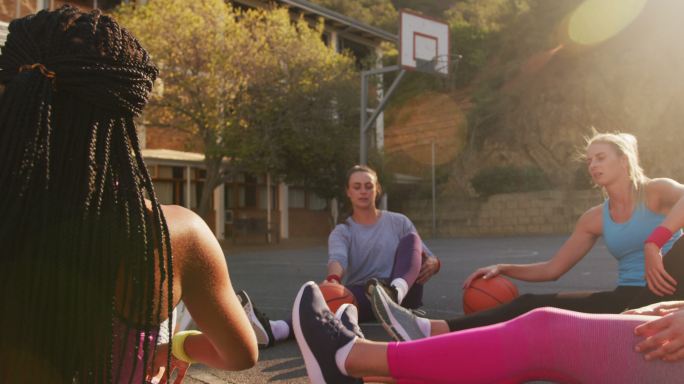 女子篮球队多样化穿着运动服，伸展身体