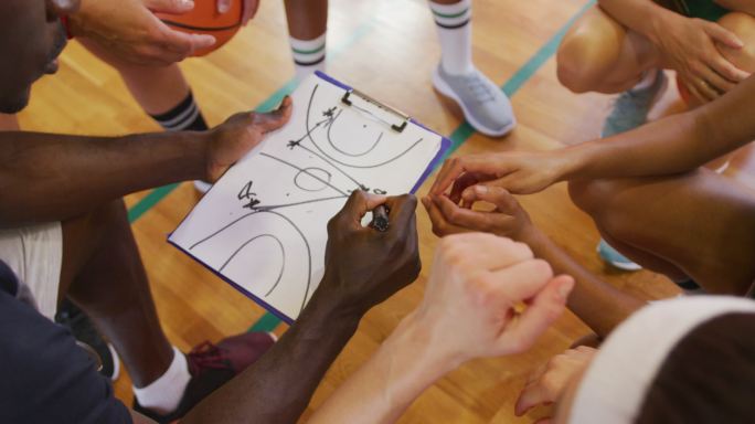 多样化的女子篮球队和教练讨论比赛策略