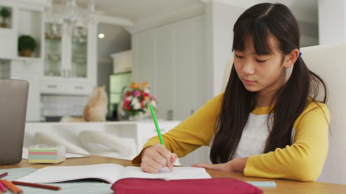 亚洲父亲使用智能手机和笔记本电脑在厨房工作，儿子和女儿做功课
