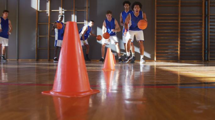 多样化男子篮球队穿着蓝色运动服练习运球