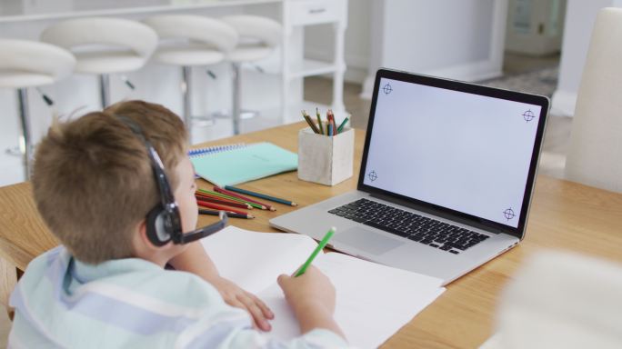 快乐的白人男孩在网上学校课程使用耳机和笔记本电脑，复制空间在屏幕上