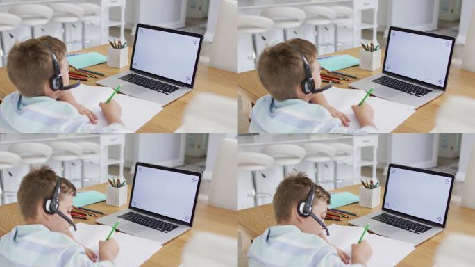 快乐的白人男孩在网上学校课程使用耳机和笔记本电脑，复制空间在屏幕上
