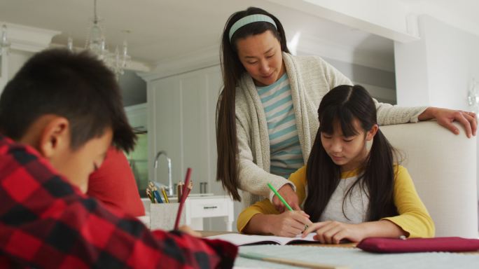 亚洲母亲在厨房帮助儿子和女儿做功课