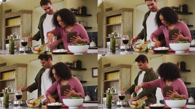 快乐的不同的夫妇在厨房一起准备一顿饭，用平板上的食谱