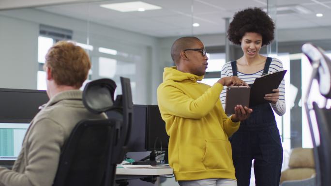 各种微笑的男性和女性商务同事使用平板电脑，在办公室讨论文书工作