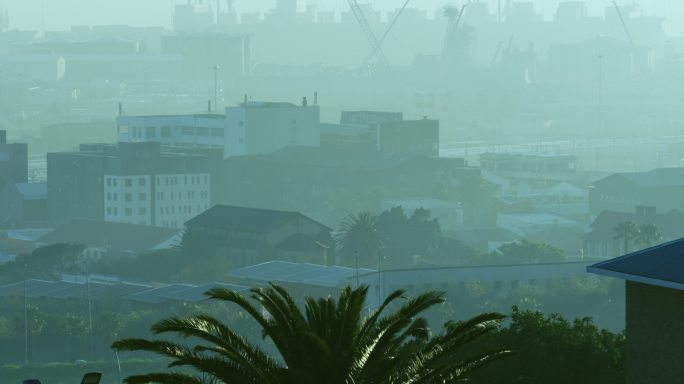 城市全景，多座现代化建筑和被烟雾笼罩的造船厂
