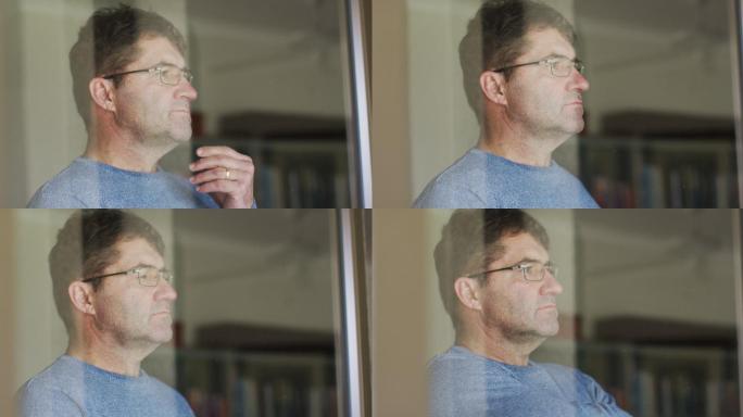 一个戴着眼镜的白人男子在家里透过窗户往里看
