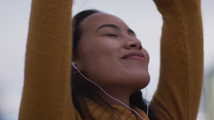 亚洲妇女戴着耳机听音乐和微笑