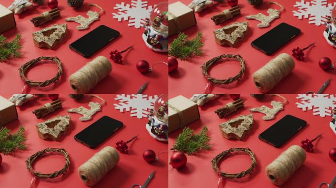 视频的圣诞装饰和树枝与智能手机在红色背景