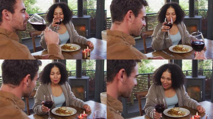 一对喜笑颜开的混血儿夫妇在餐馆里喝着葡萄酒，吃着午餐