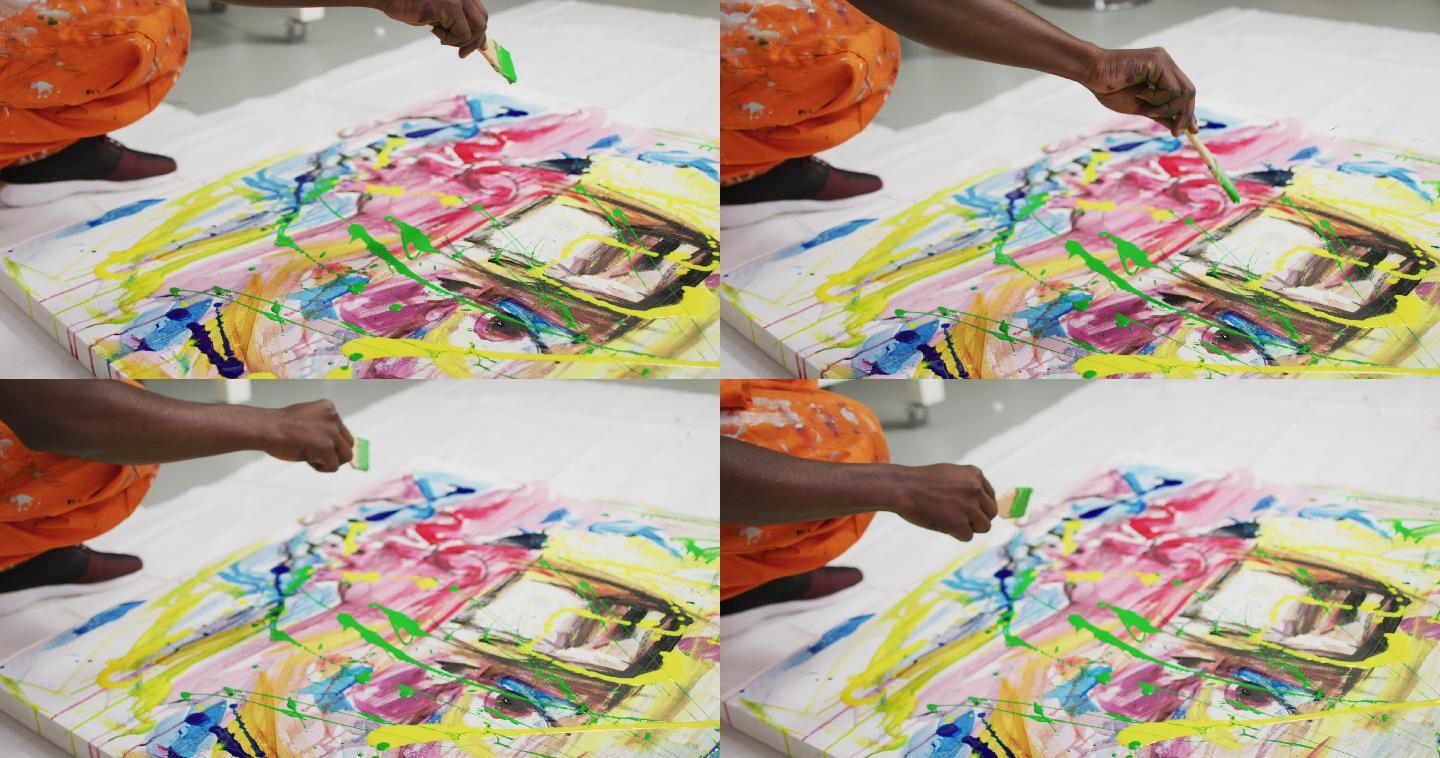 近距离的非裔美国男性艺术家在艺术工作室用画笔在画布上泼洒颜料