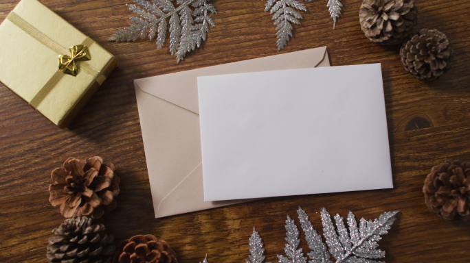 圣诞装饰的视频与白色卡片和米色信封在木制背景