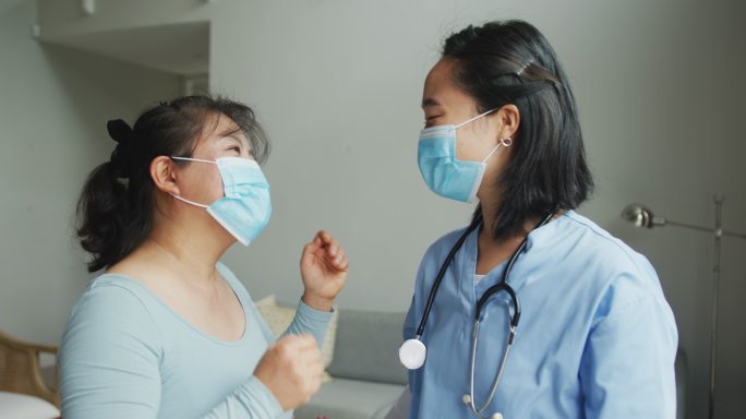 亚洲女护士和病人戴着口罩在医院对着摄像机说话和看