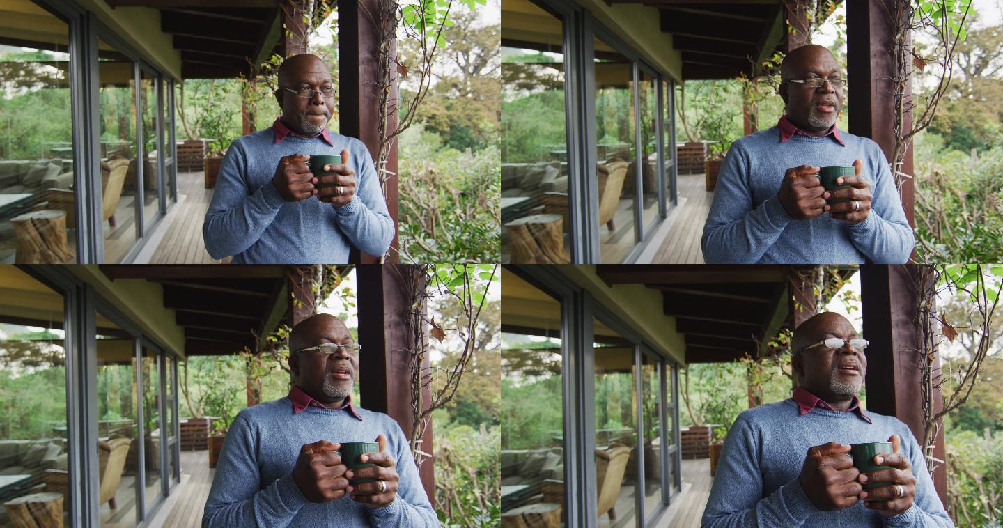 非裔美国老人站在阳台上喝咖啡，欣赏风景