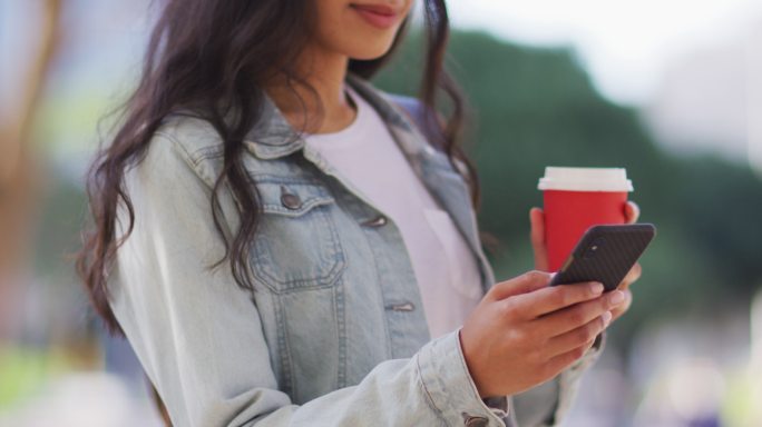 亚洲女性用智能手机端着外卖咖啡