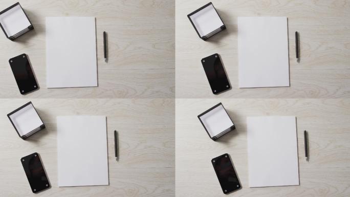 视频的智能手机和白纸与笔和复制空间在木制背景