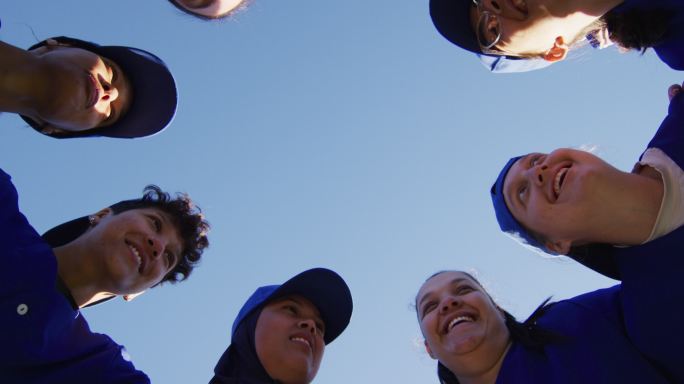 低角度的看法，不同的组女棒球运动员在一个拥挤的蓝天