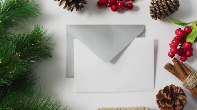 圣诞松果、圣诞树和红浆果装饰的视频，白色背景上的信封