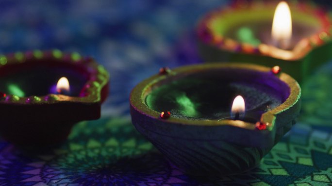 点燃装饰陶罐上的蜡烛，放在有图案的桌面上，把焦点放在前景上，散景背景上