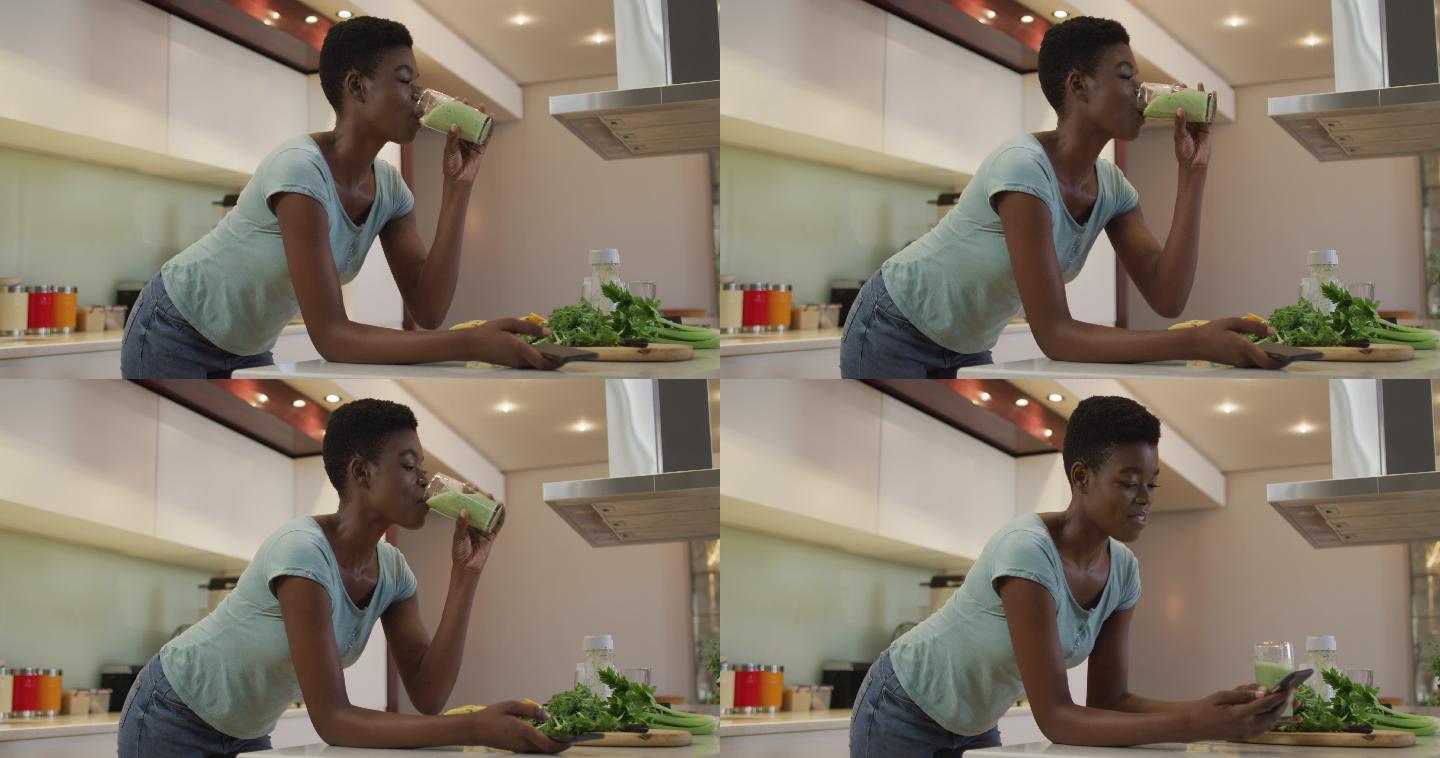 微笑的非洲裔美国人迷人的女人喝自制冰沙在厨房