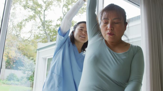 亚洲女性理疗师在手术中治疗女性患者，移动她的手臂