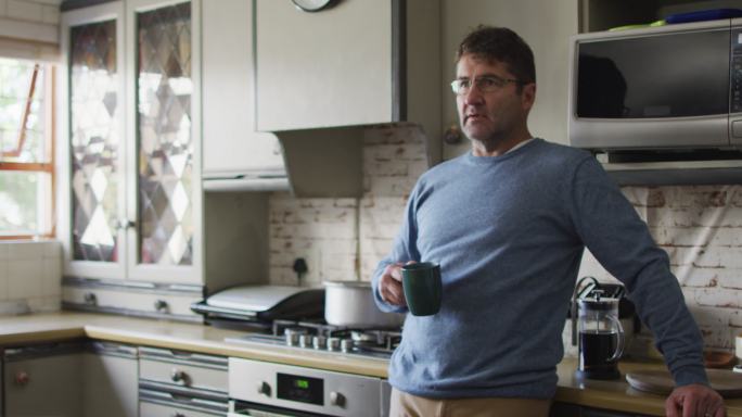 深思熟虑的白人男子在厨房喝咖啡在家里