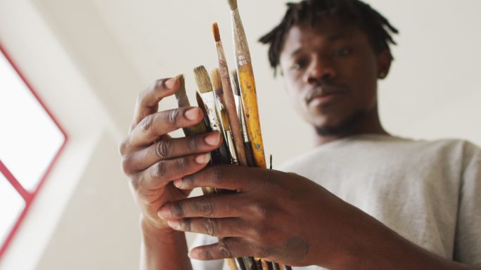 非裔美国男性画家在艺术家工作室选择画笔