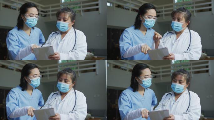 戴口罩、使用平板电脑、在医院讨论的亚洲女医生的肖像