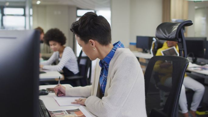 白人创意女商人在现代办公室写字台写作的肖像