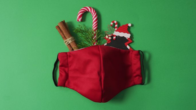 圣诞装饰和糖果拐杖与红色的脸面具在绿色的背景