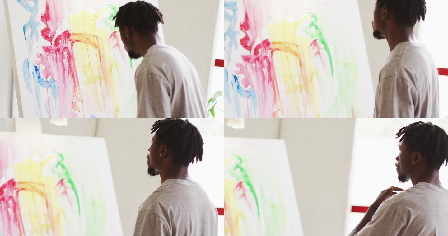 深思熟虑的非裔美国男性艺术家坐在艺术工作室看着他的绘画