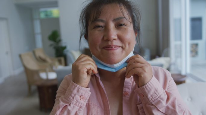 亚洲女性患者戴口罩，放下口罩，对着镜头微笑
