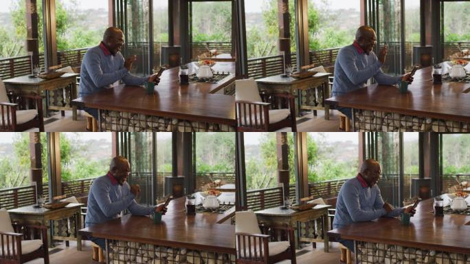 快乐的非洲裔美国老人坐在柜台在厨房与智能手机视频通话