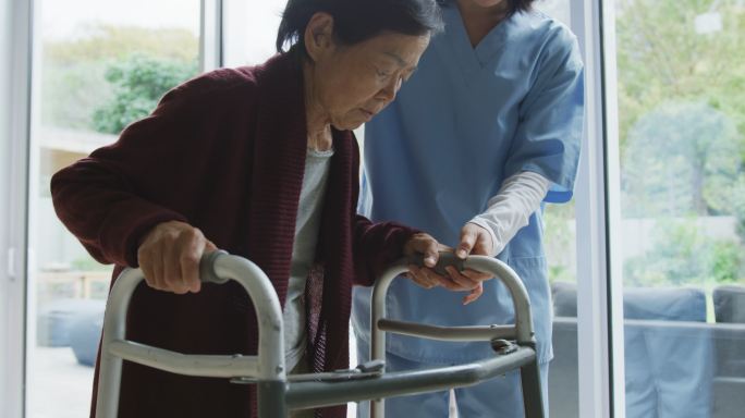 微笑的亚洲女医生帮助老年女性患者用步行架行走